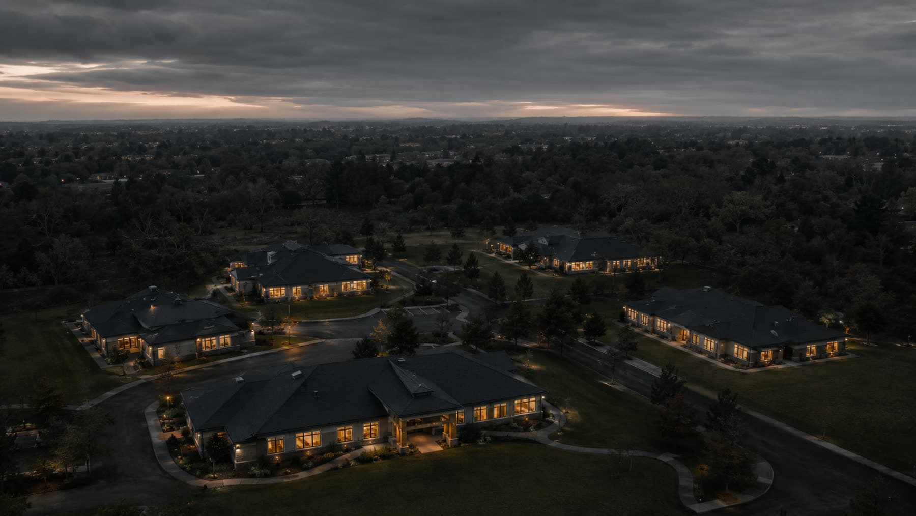 Five skilled nursing buildings lit at dusk, seen from the air across one campus.